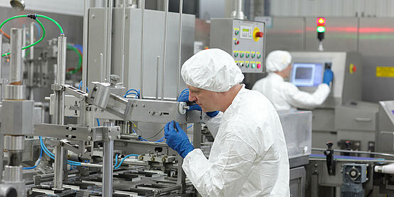 A photo of a man wearing white protective clothing and blue gloves working on a room protection system