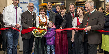 Josef Ortner, Katharina Ortner, Stefanie Rud, Brigitte Ortner, Wolfram Kofler und weitere Personen zerschneiden gerade ein rotes Band zur Eröffnung der Produktion.