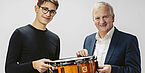 Links ist ein junger Mann, rechts neben ihm steht Josef Ortner. Beide halten gemeinsam eine Trommel.