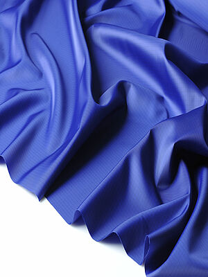 A dark blue shiny fabric, which lies on white background waves and folds.