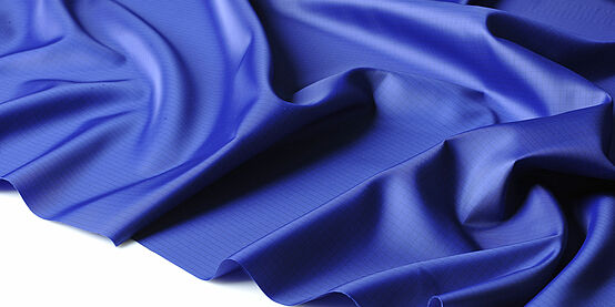 A dark blue shiny fabric, which lies on white background waves and folds.