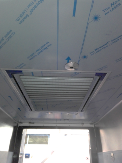 In a gray foiled ceiling of a box is installed rectangle, which has slats. Next to it is a disc with a hole in the middle.
