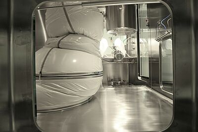 Durch eine Glasscheibe sieht man den unteren Teil des Roboters im Inneren des Isolators.