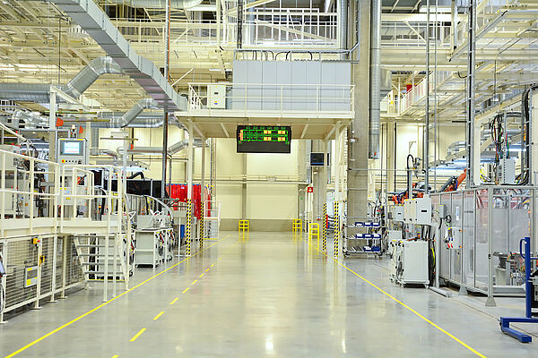 Eine Produktionshalle, in der unterschiedliche Anlagen und Rohre zu sehen sind.