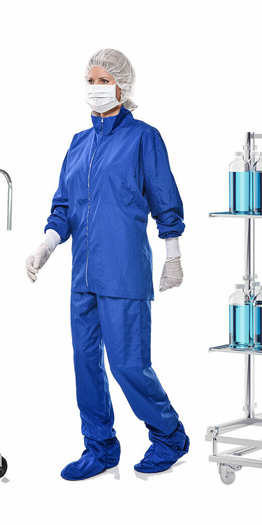 A woman wearing full protective clothing standing in between an empty movable trolley and another trolley filled with glass tube filled with blue substance