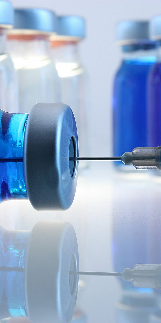 This photo shows multiple injection bottles filled with a blue liquid showing a needle drawing the liquid in