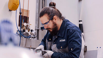 Mann arbeitet mit Schutzkleidung und Schutzbrille in der Produktion.