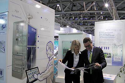 Lucia Matejcek and Michael Rötzer are standing at an exhibition stand. The two are looking at a brochure from Ortner.