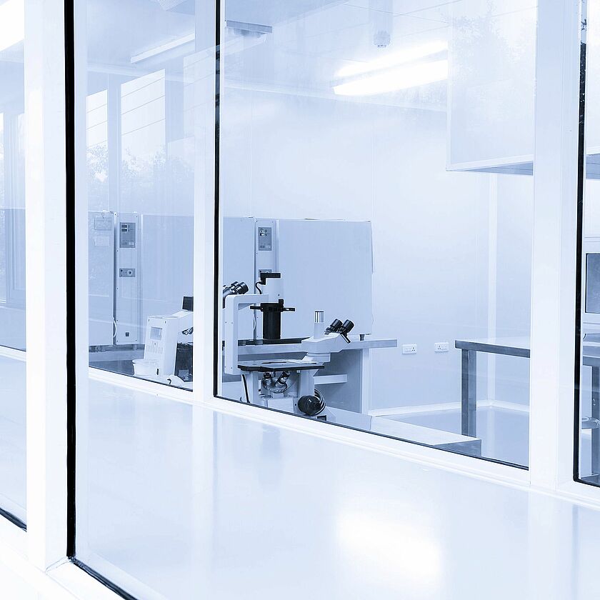 A photo of the interior of a cleanroom. Full length windows show a microscope inside on a table